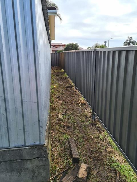 A Fence Is Surrounding a Yard Next to A Building — D & B Fencing in Taree, NSW