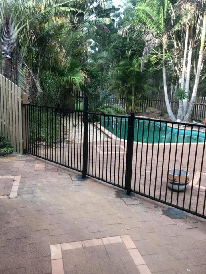 A Black Metal Fence Surrounds a Swimming Pool in A Backyard — D & B Fencing in Port Macquarie, NSW