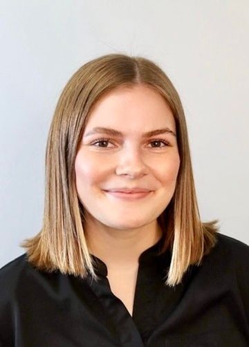 Portrait of a smiling person in a black shirt against a light background