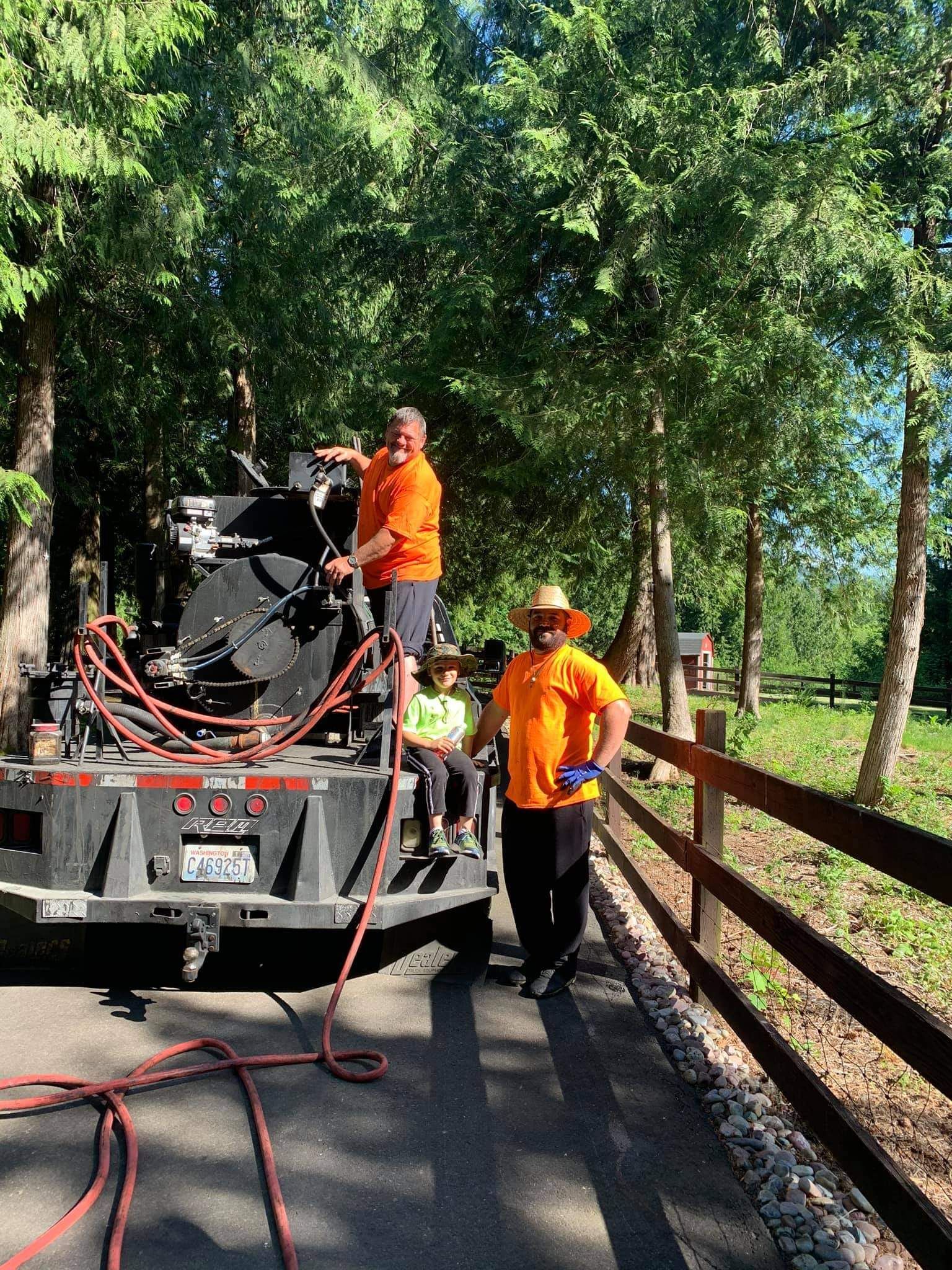 Two men are standing next to a truck on the side of the road.