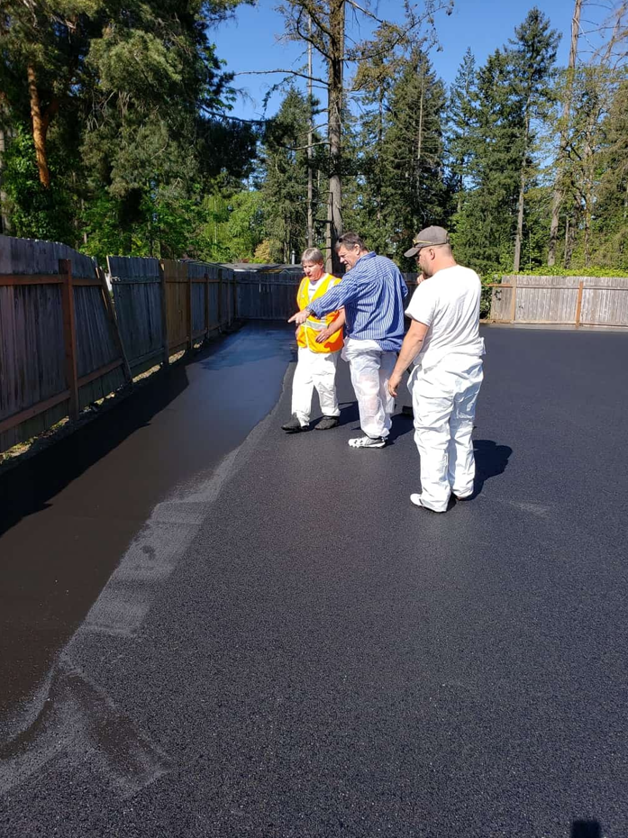 A group of men are standing on a asphalt road.