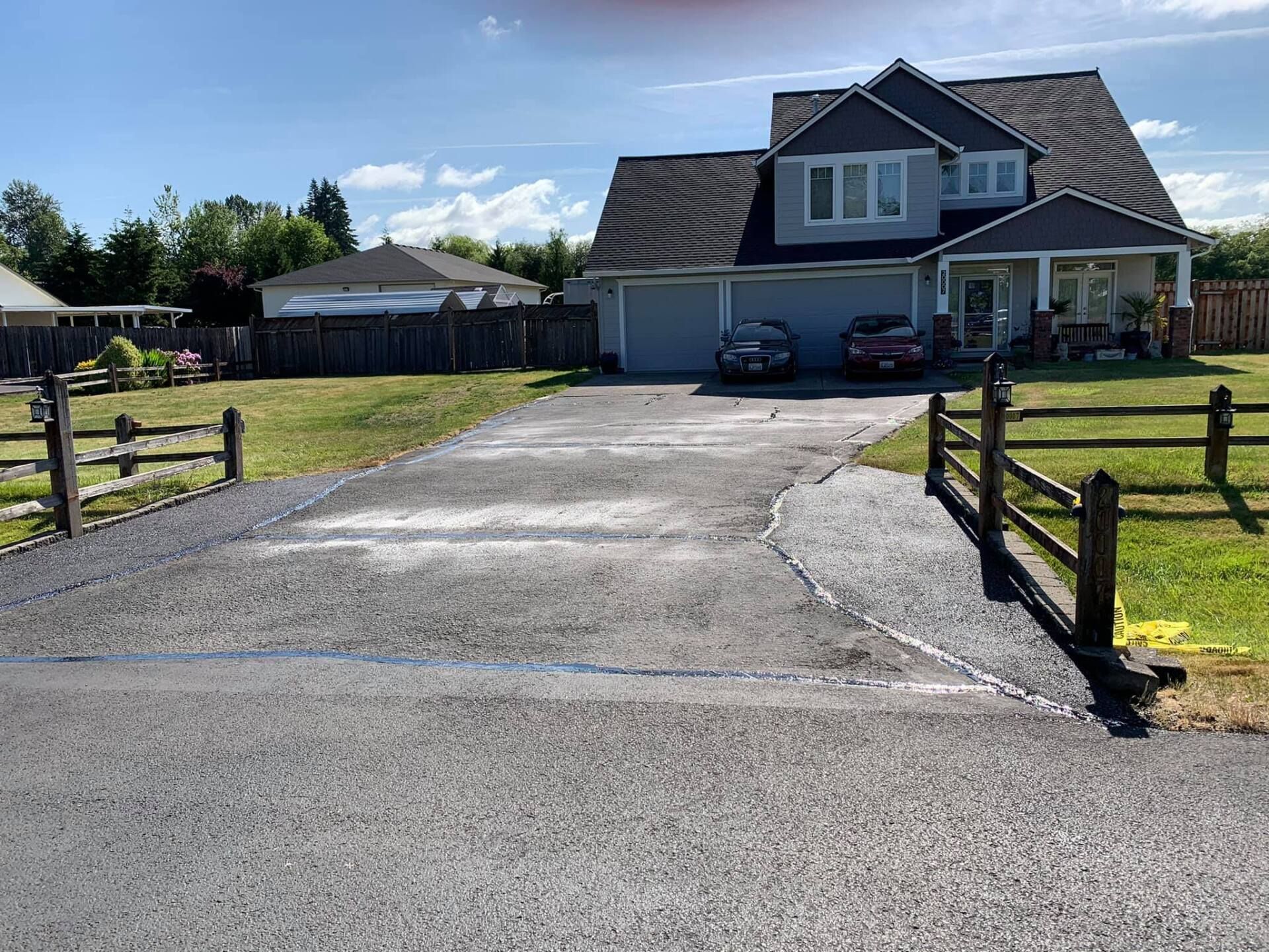 A driveway leading to a large house with cars parked in front of it.