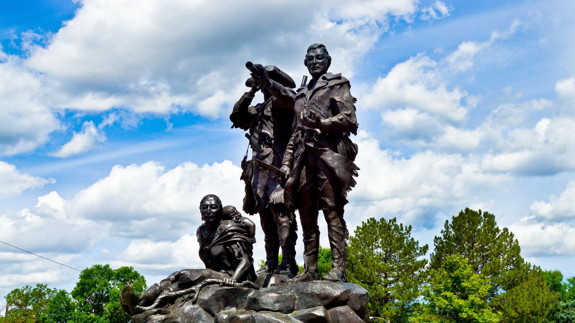 A statue of a man standing on top of a rock with two other men.