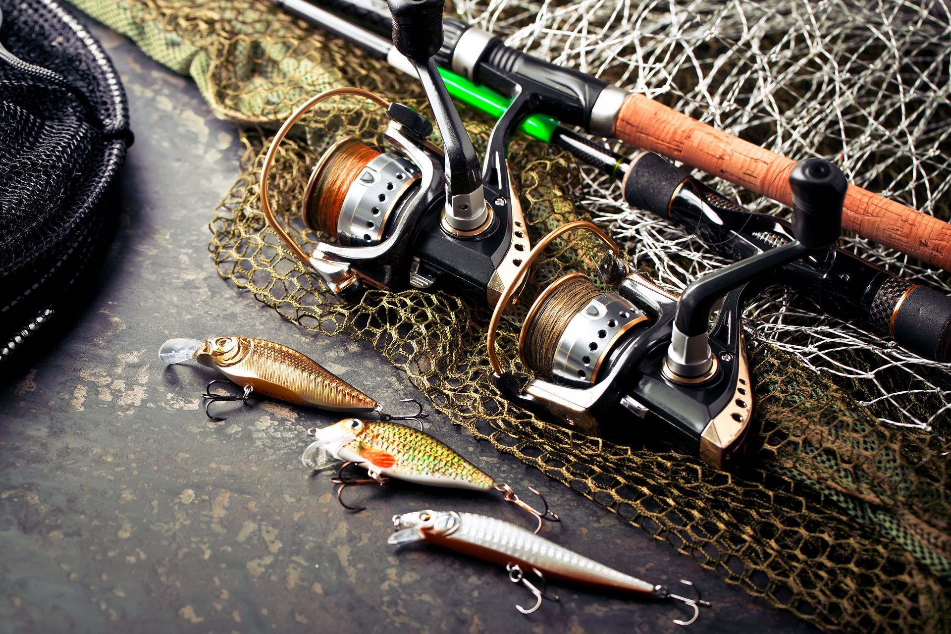Fishing rods , reels , lures and a fishing net on a table.