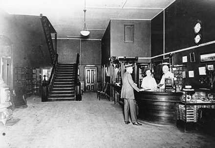 A black and white photo of a man standing at a counter in a store