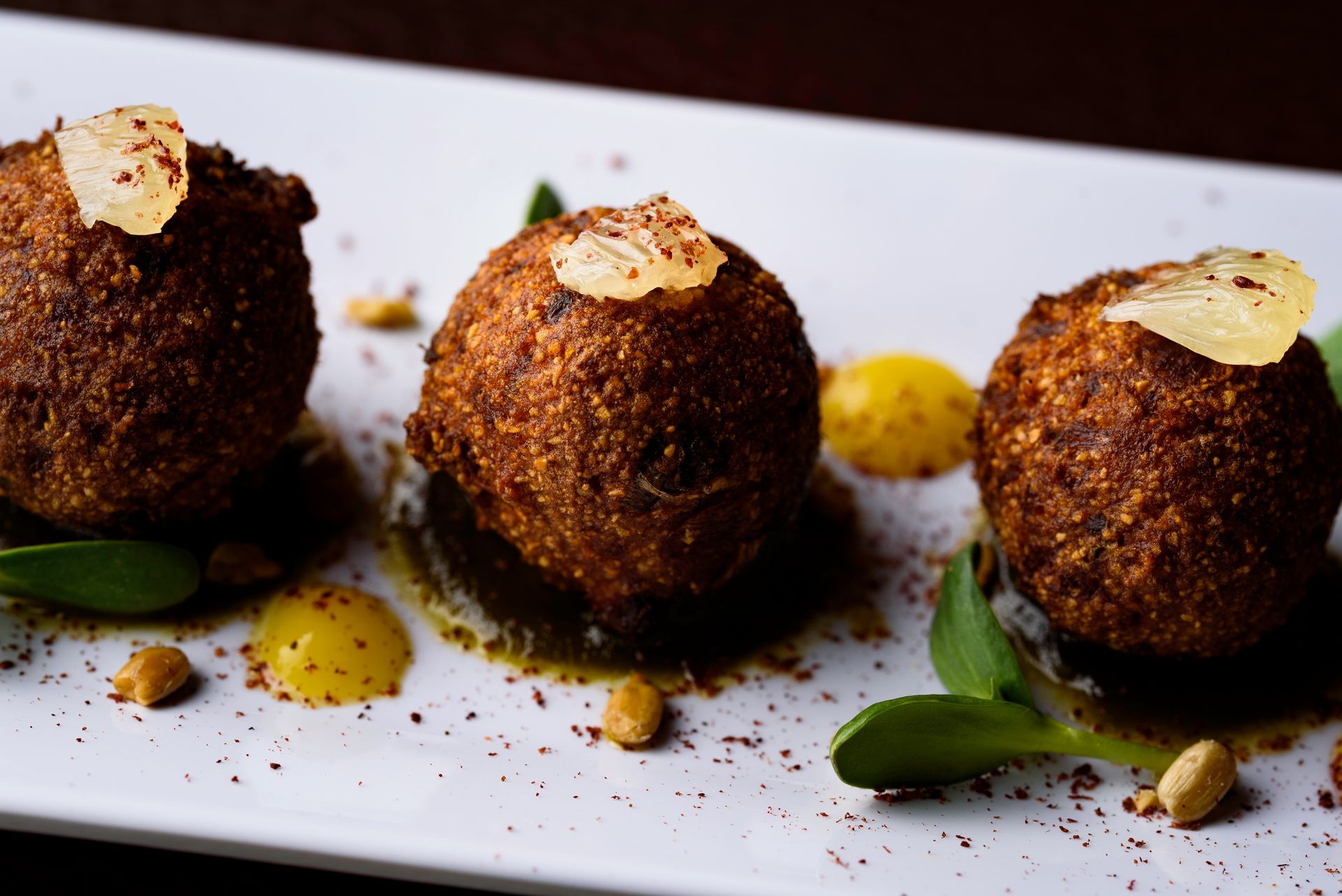 A white plate topped with three fried food balls