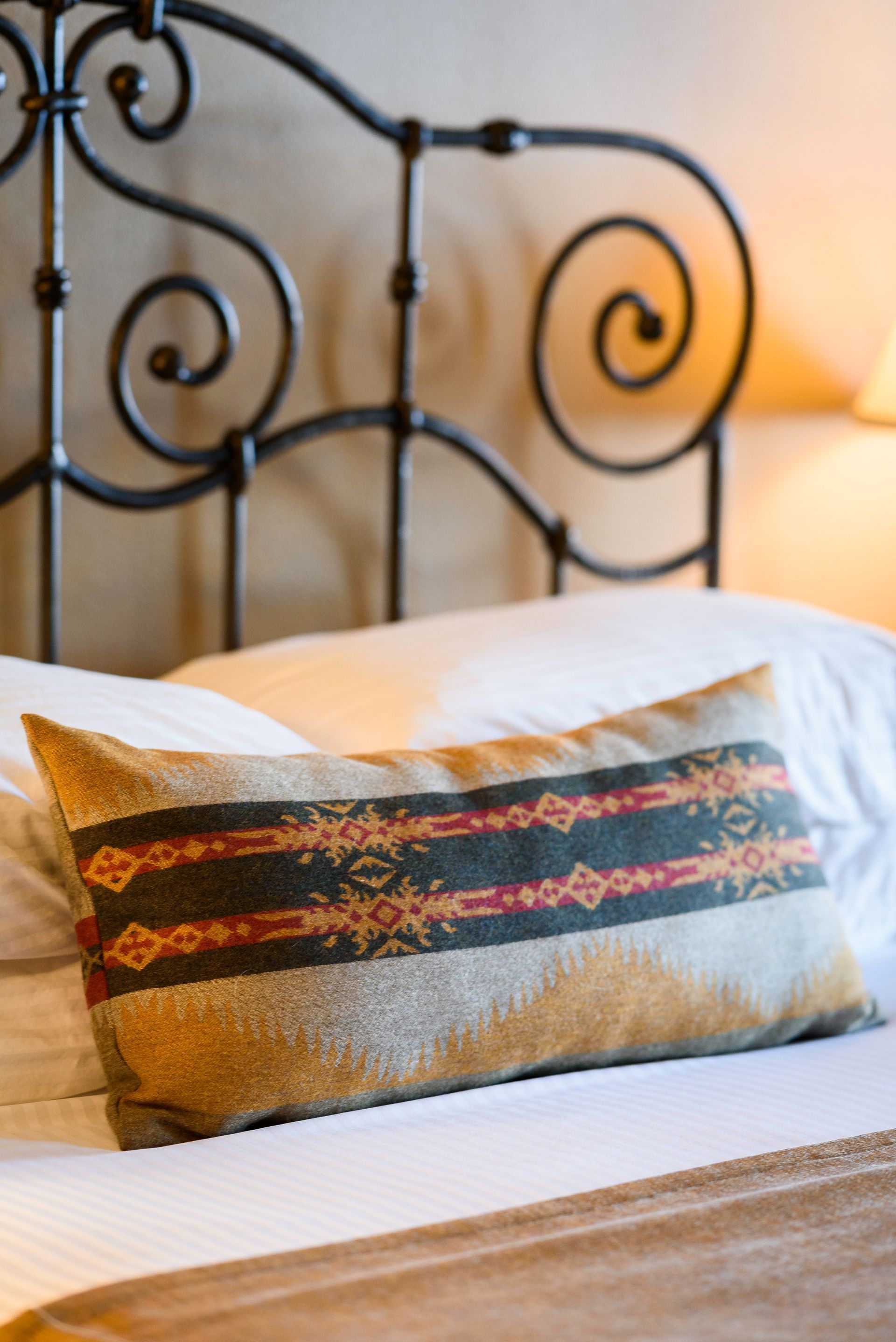 A bed with a wrought iron headboard and a pillow on it