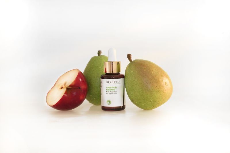 Green and red apples around a small dropper bottle on a white background