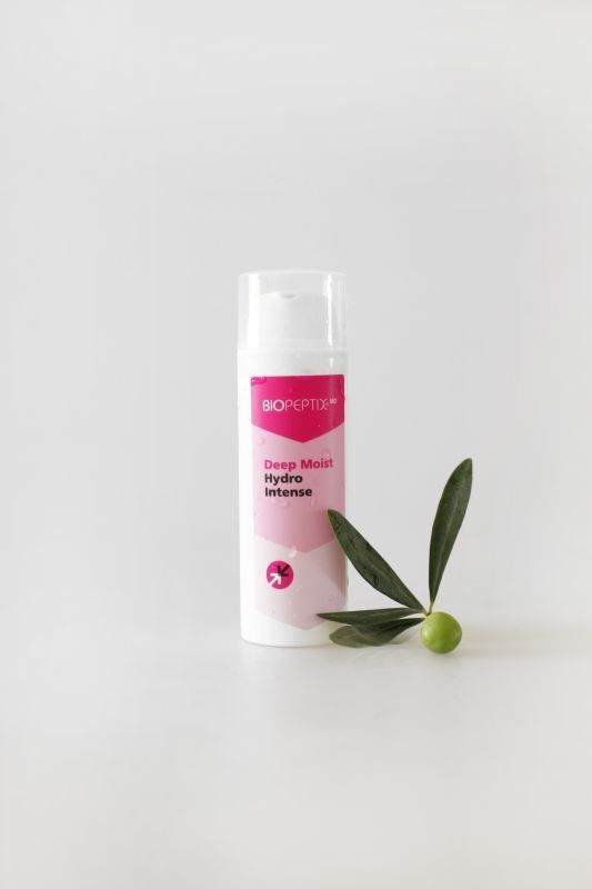Pink-and-white cosmetic stick with green leaves on a white background