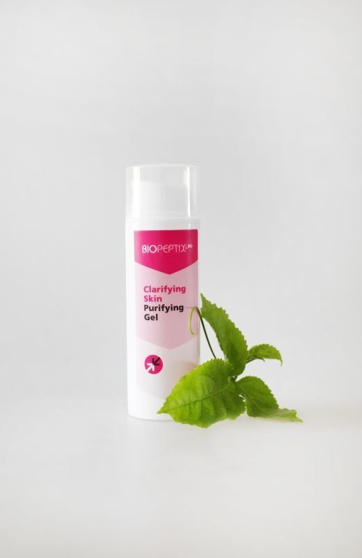 White cosmetic tube with pink label and green mint leaves on a light background