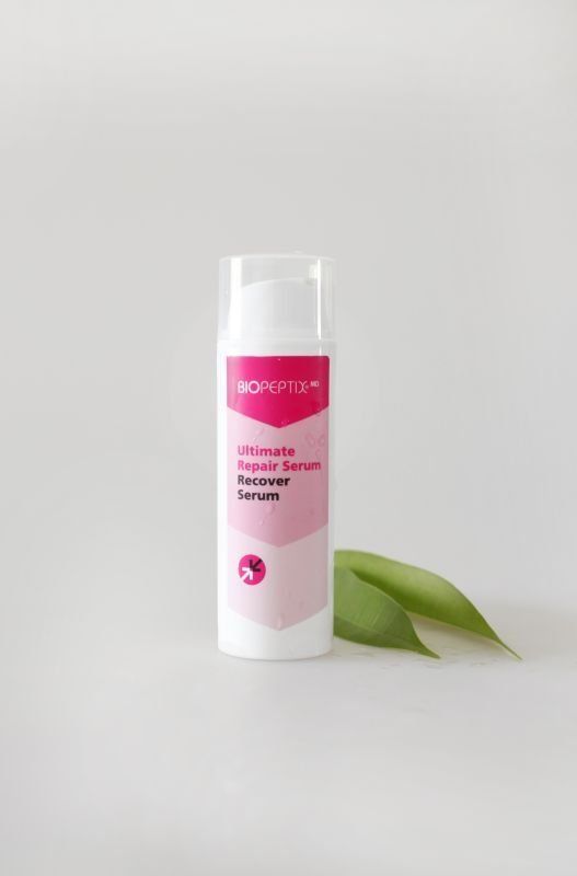 White skincare bottle with pink label and green leaves on a light gray background