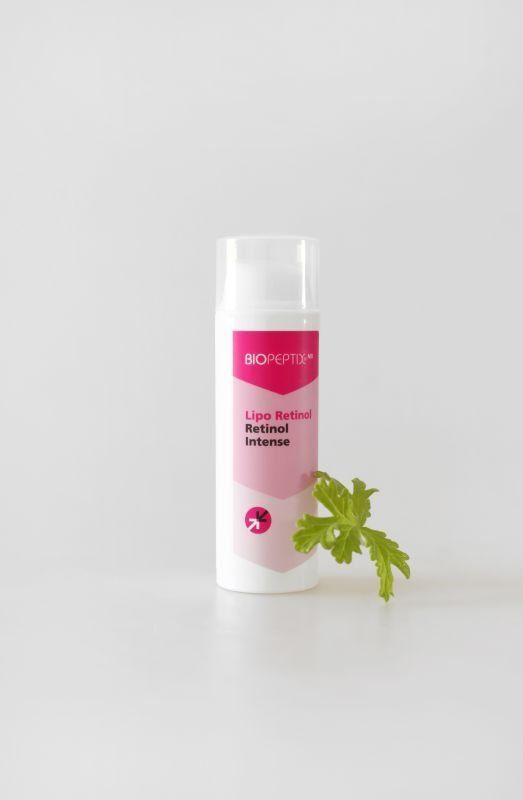 Pink-labeled white skincare bottle with green herb sprig on a light gray background