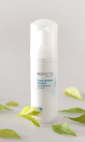 White skincare bottle with green label and leaves on a light background
