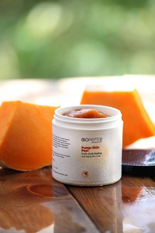 White cosmetic jar on wooden table with orange fruit slices in the background