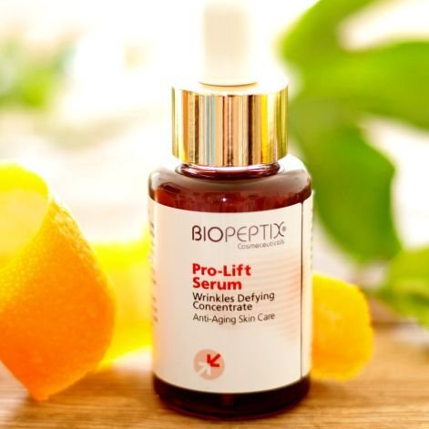 BIOPEPTIX Pro-Lift serum bottle with gold cap beside orange slices and green leaves