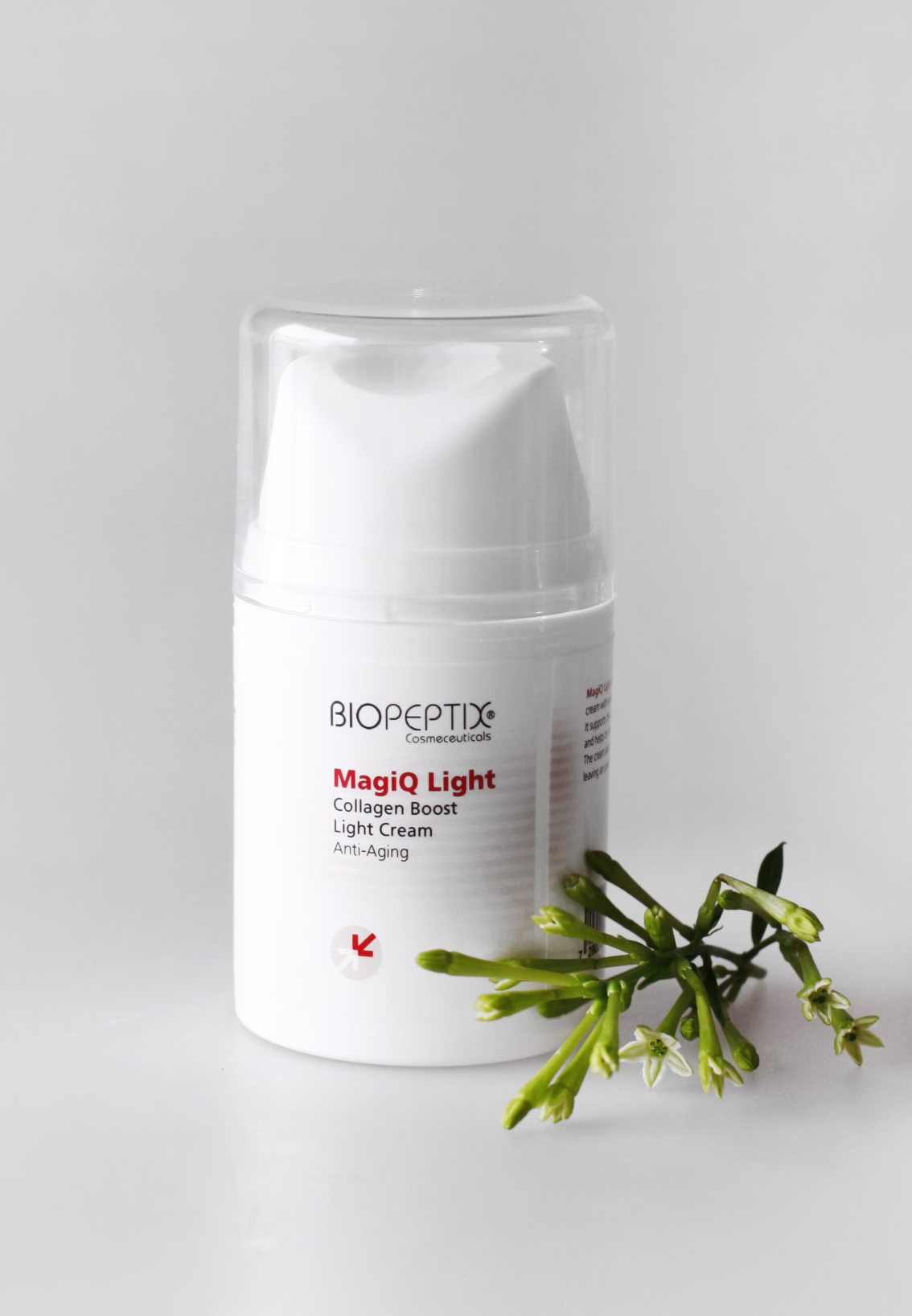 White skincare bottle with green leaves on a light gray background