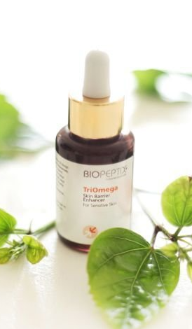 Droplet bottle of Biopept toner on white surface with green leaves and soft blurred background