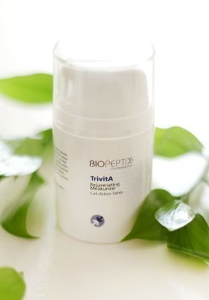 White skincare bottle with green leaves on a bright surface