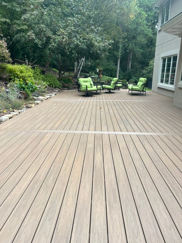 Wooden deck with green chairs and lush trees in the background.