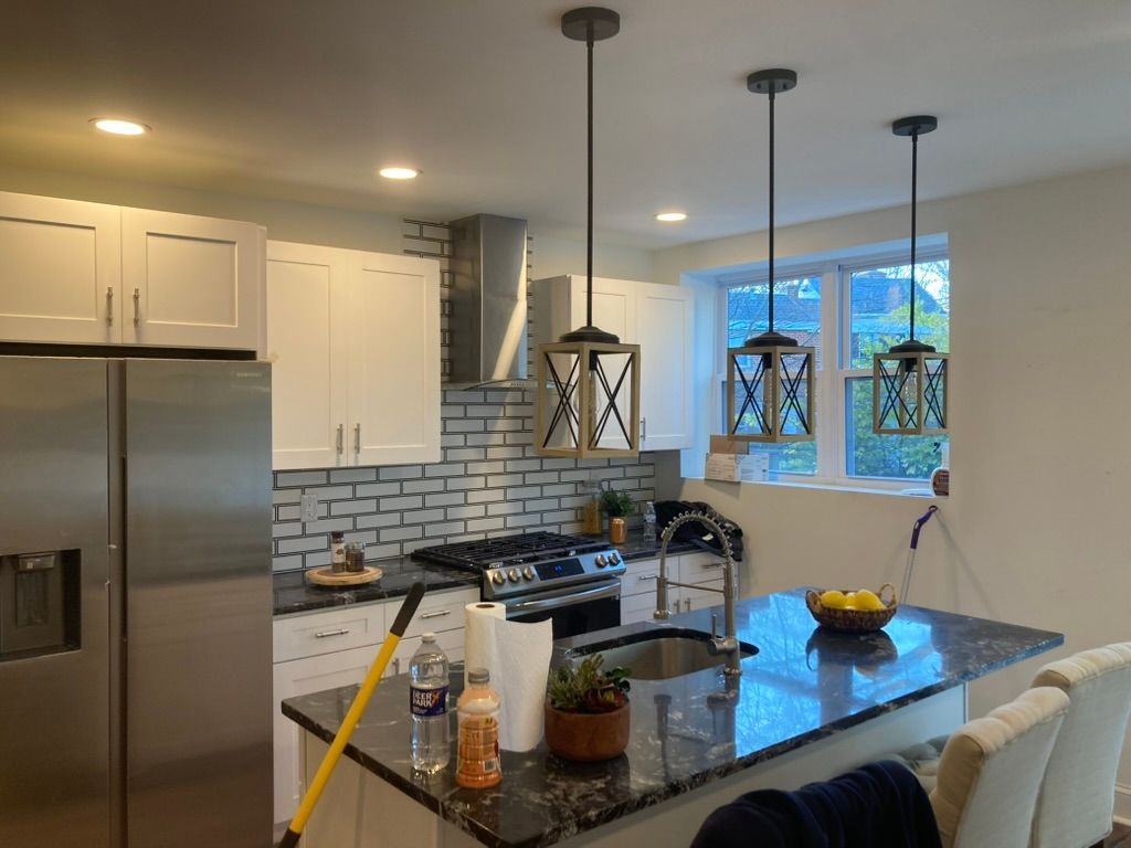 Kitchen with white cabinets, stainless steel appliances, and island with pendant lights.
