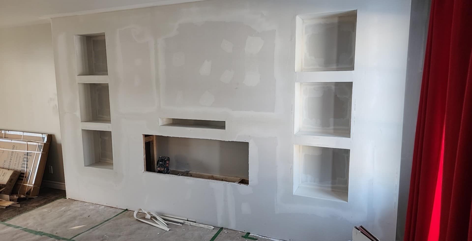 Cloison sèche avec étagères intégrées et une ouverture rectangulaire, éventuellement pour une cheminée ou une télévision, dans un intérieur.