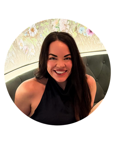 Woman with dark hair smiles, wearing a black halter top. Floral wallpaper backdrop.