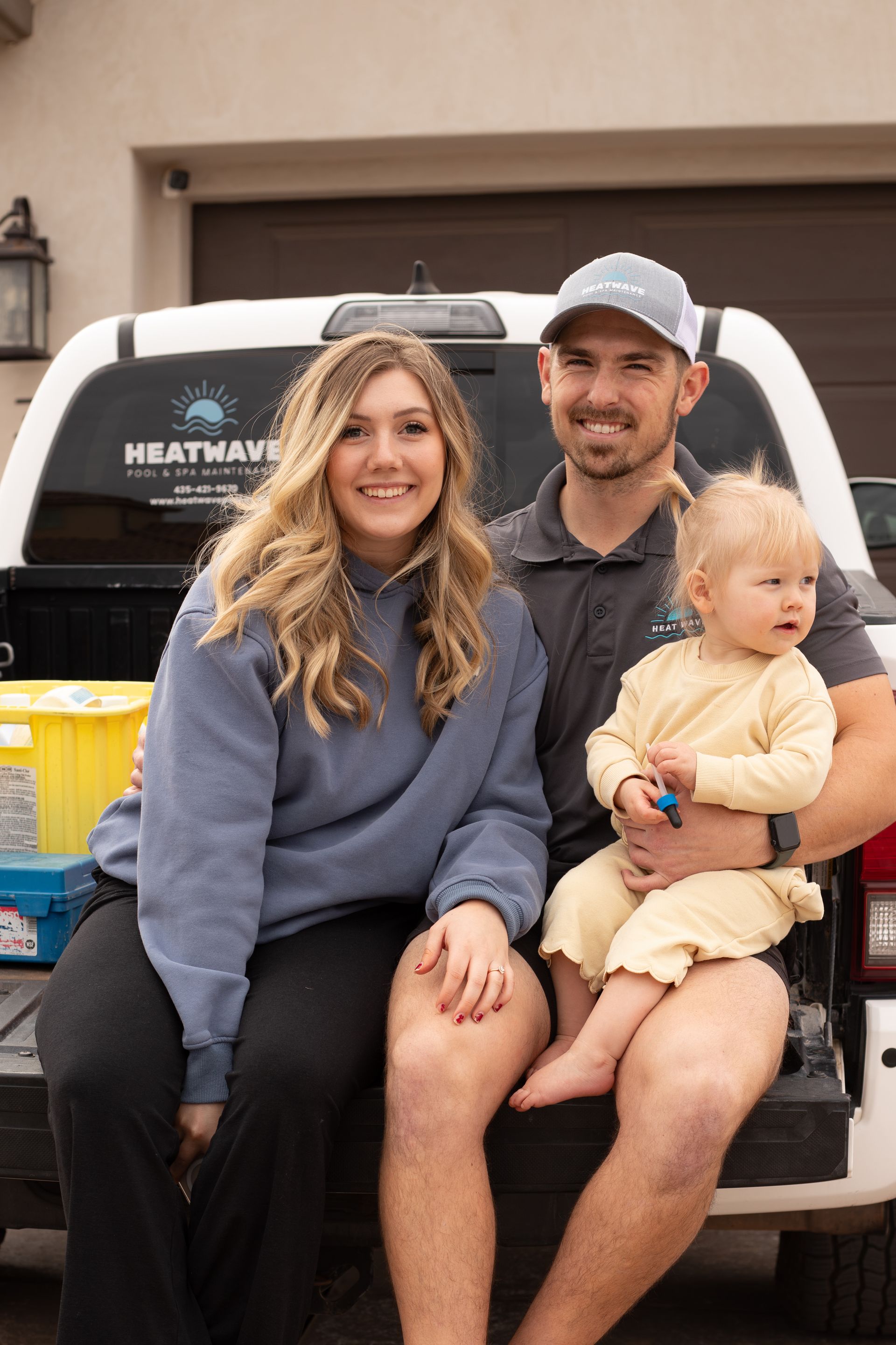 owners of Heatwave pools and spas, a young family, sitting on the bad of a pool service truck in St. George, Utah.