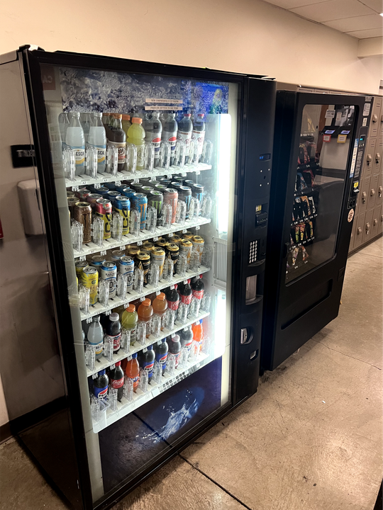 two vending machines are lined up next to each other in a hallway