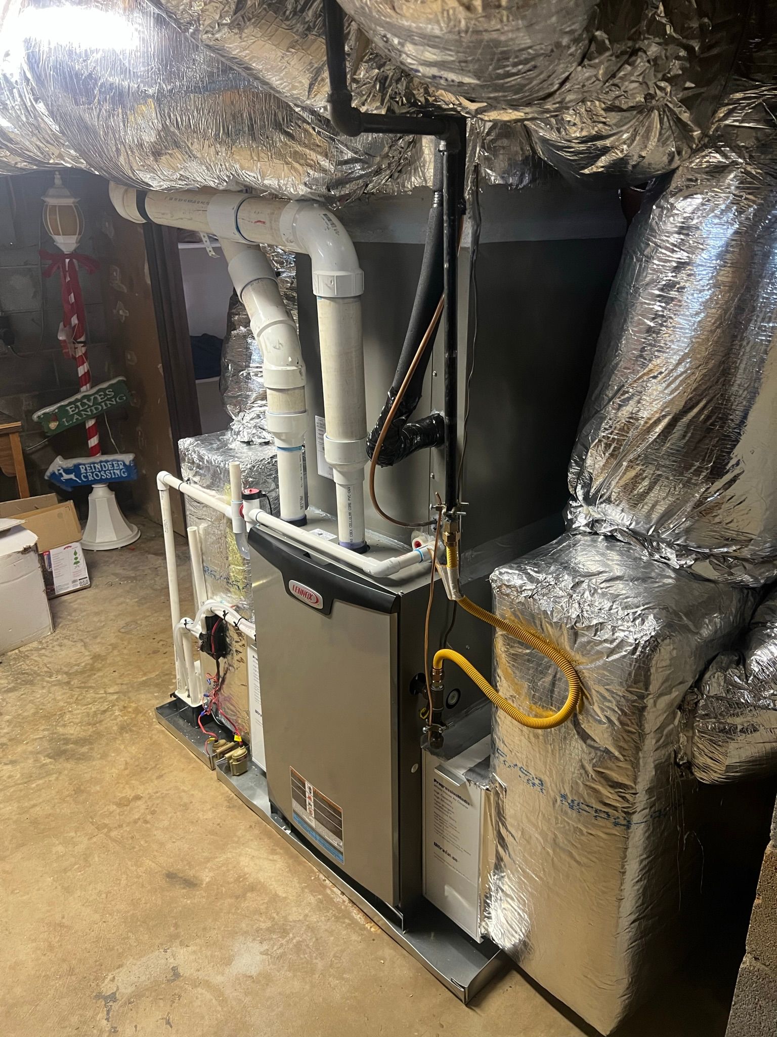 Furnace unit in a basement, with ductwork and wiring visible.