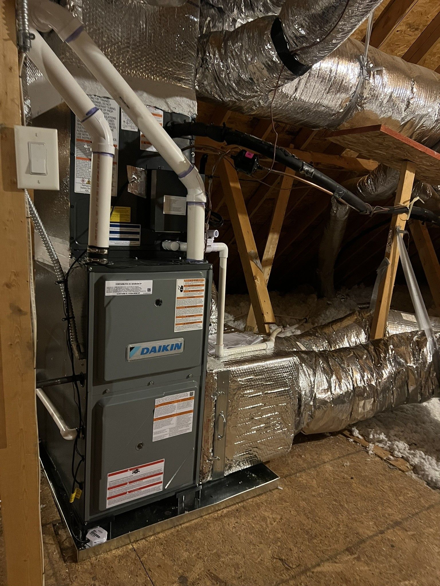 HVAC unit in an attic with ductwork, electrical wiring, and wooden beams.