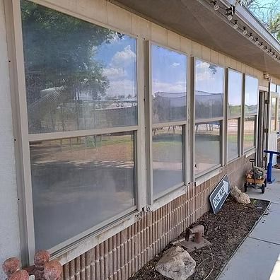 Row of tinted windows along a brick building exterior beside a sidewalk and landscaped strip