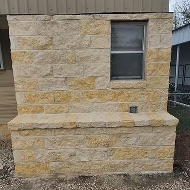 Stone exterior wall with a small window and a raised stone ledge in front