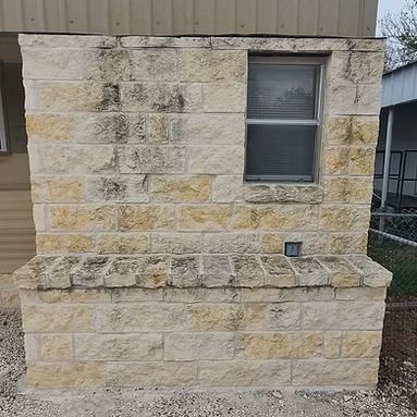 Stone exterior wall with a small window and raised ledge on a building facade