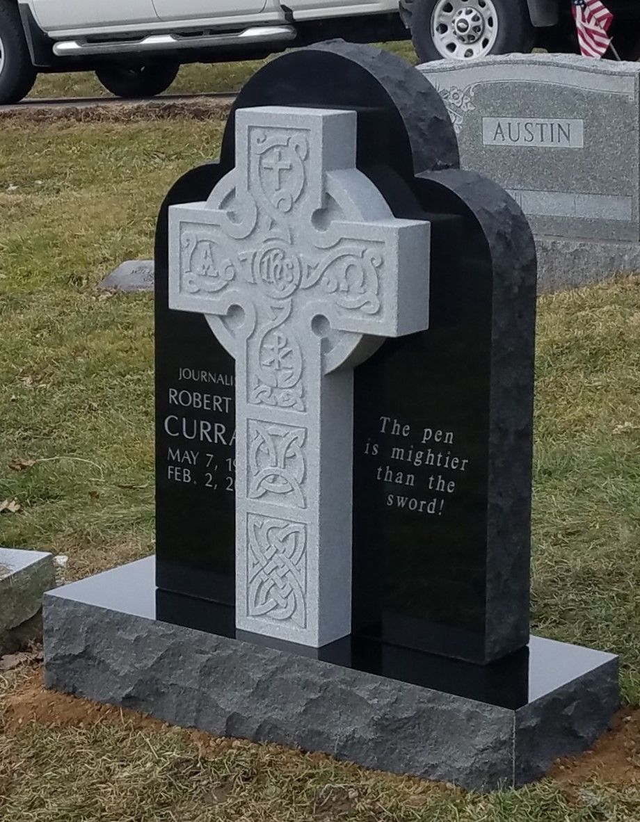 A black gravestone with a white cross on it