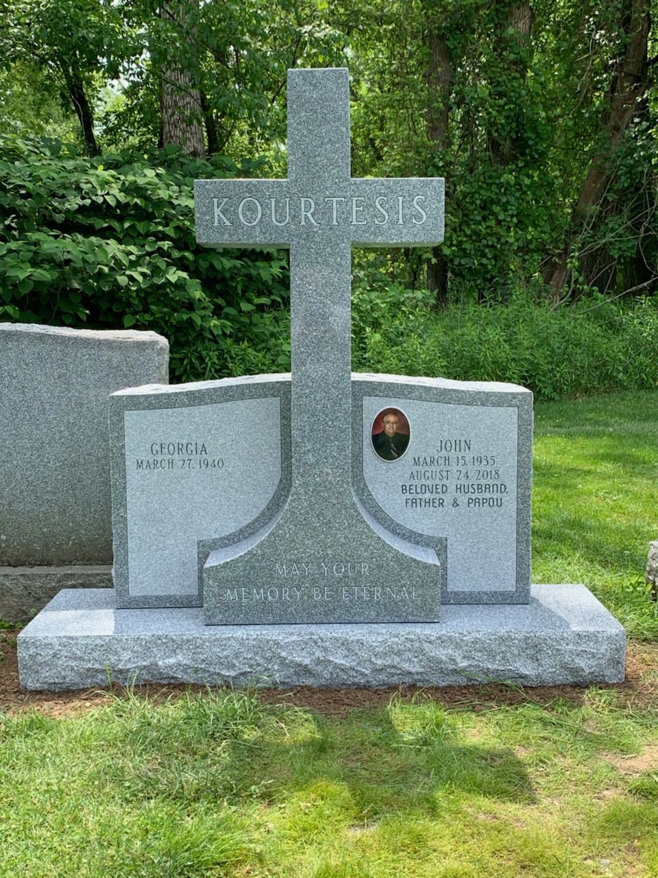 A gravestone with a cross on top of it in a cemetery
