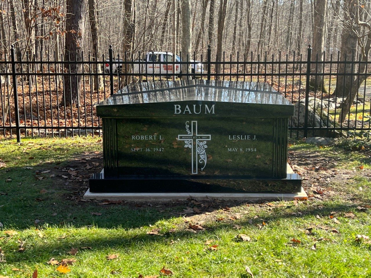 A grave in a cemetery with a cross on it.