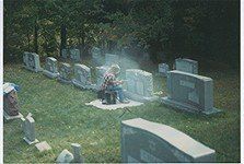 A person is sitting on a blanket in a cemetery.