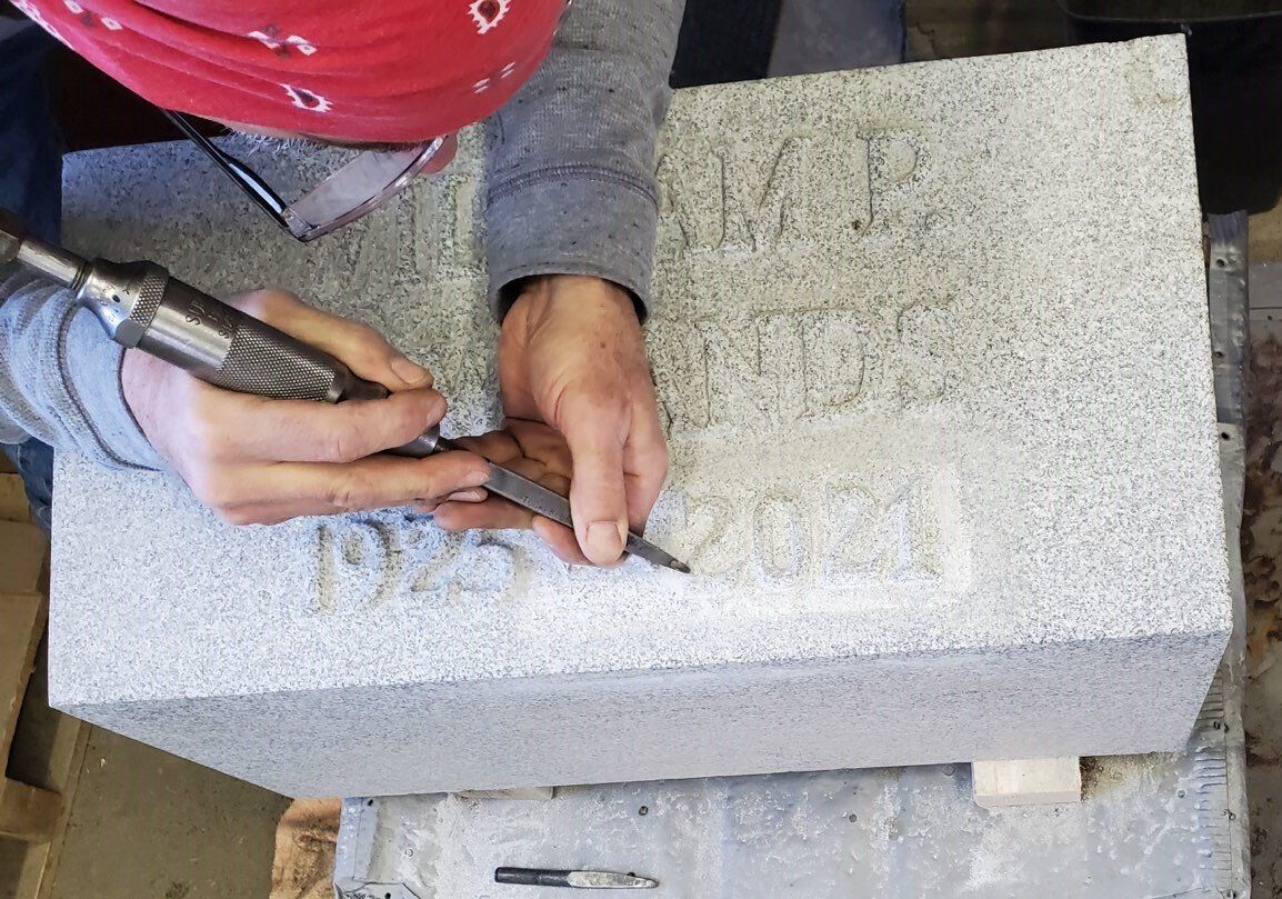 A person is carving a stone block with a tool.