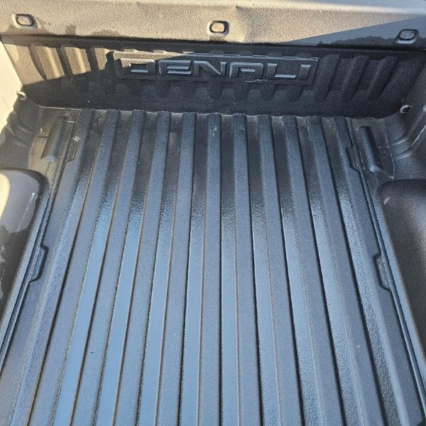 The clean, black, ribbed bed of a GMC Denali pickup truck.