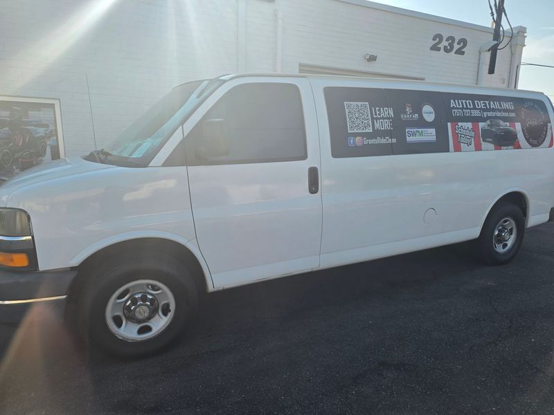 White cargo van with a red-and-blue business sign parked beside a building