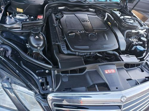 An open hood of a dark Mercedes-Benz vehicle revealing a clean V6 engine bay.