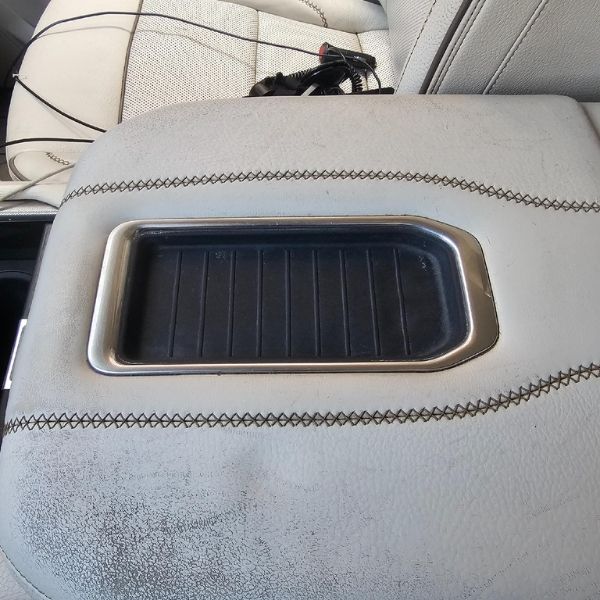 A rectangular wireless charging pad set into a grey leather vehicle center console.