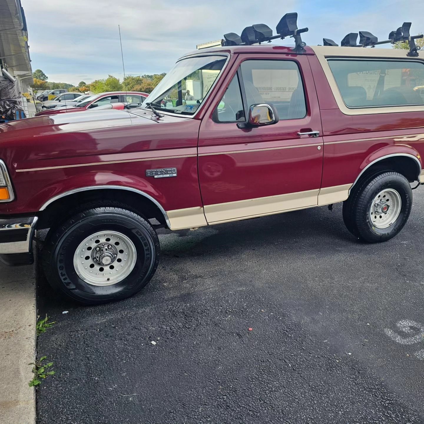A maroon and tan Ford Bronco SUV parked on asphalt in a parking lot.