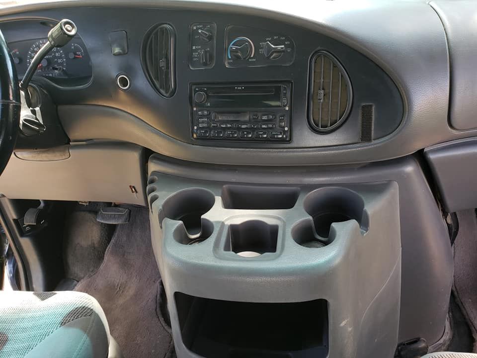 Interior view of a gray vehicle dashboard featuring a central stereo, air vents, climate controls, and cup holders.