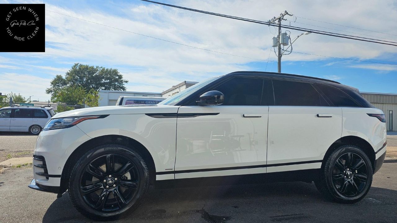 A white Land Rover Range Rover Velar SUV with black wheels parked in an outdoor lot under a bright, sunny sky.