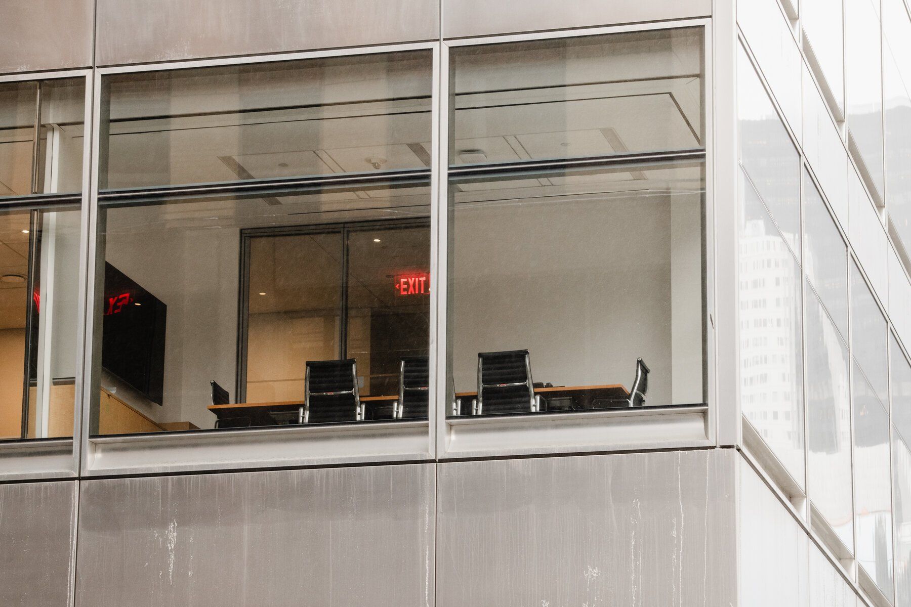 A conference room with tables and chairs is visible through the windows of a building.