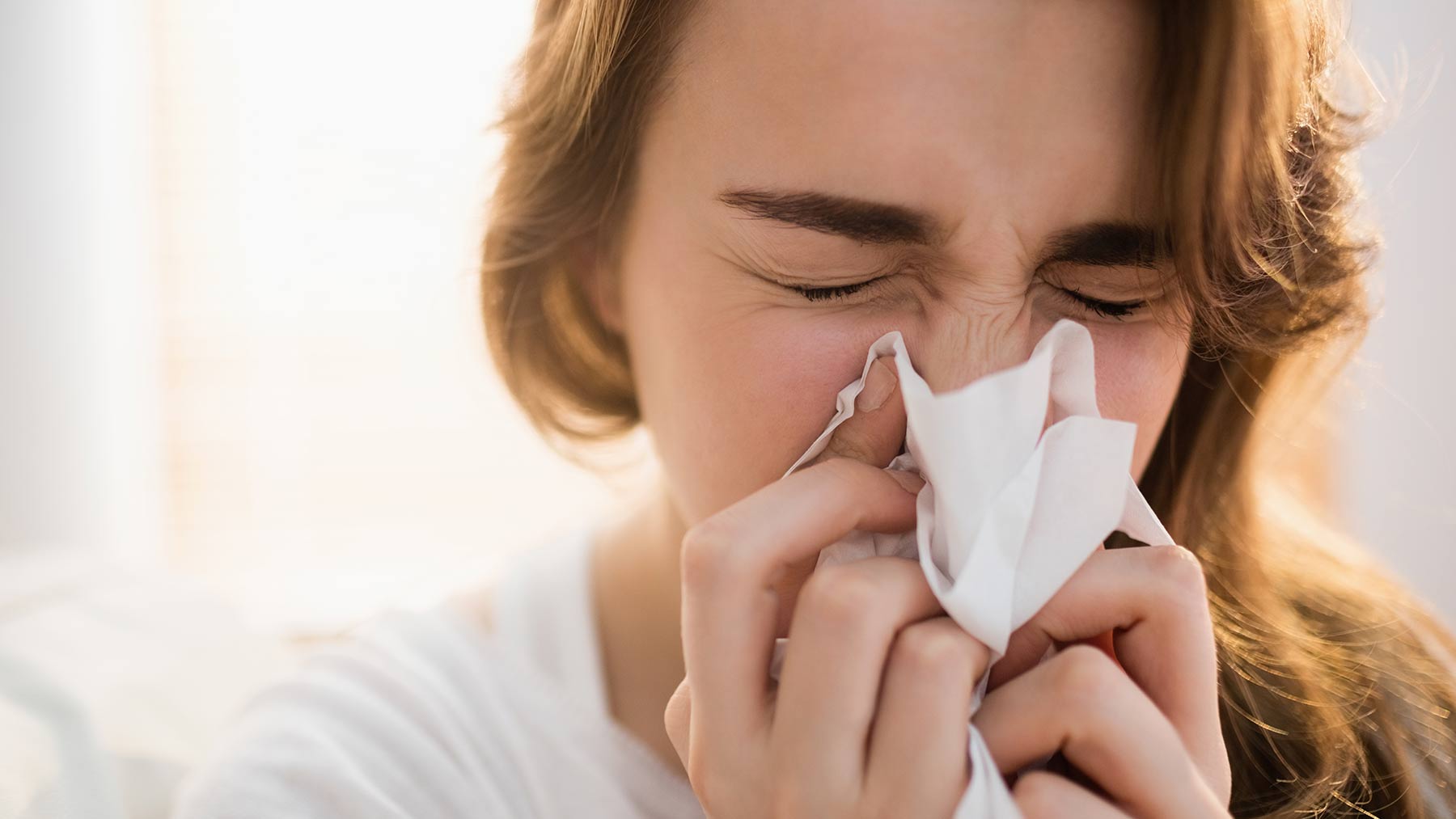 A woman is blowing her nose into a napkin.