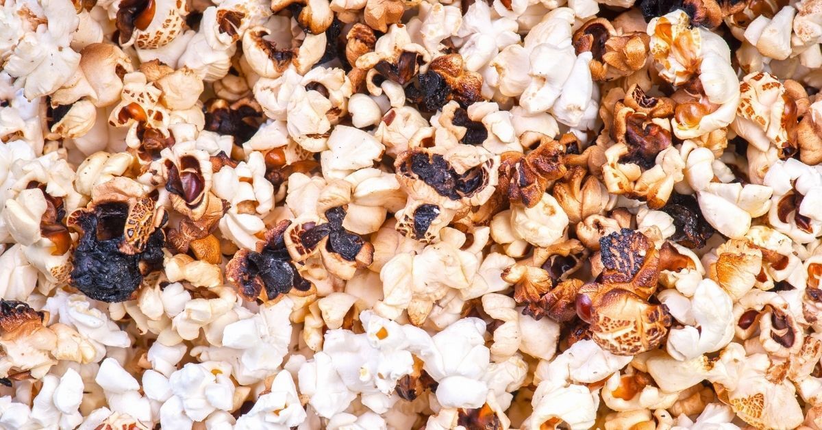 A close up of a pile of popcorn with raisins on it.