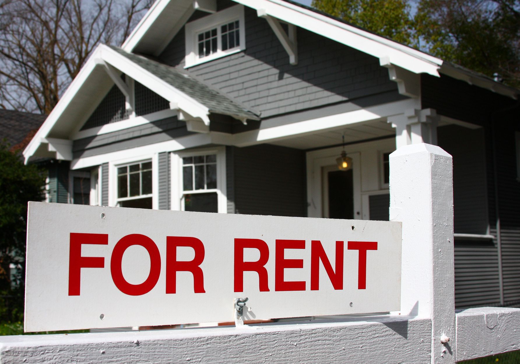 A house with a for rent sign in front of it
