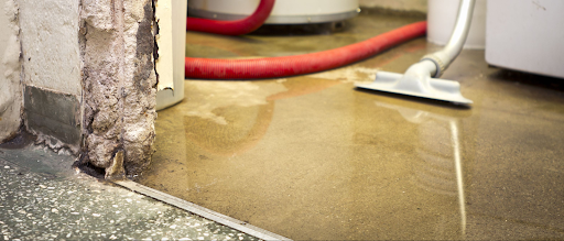 A vacuum cleaner is being used to clean a flooded basement floor.